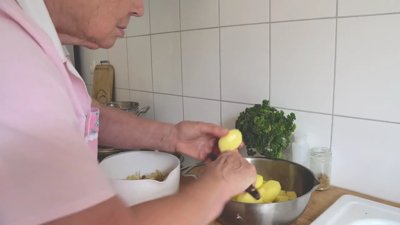 Senior lady at home cutting and peeling potatoes