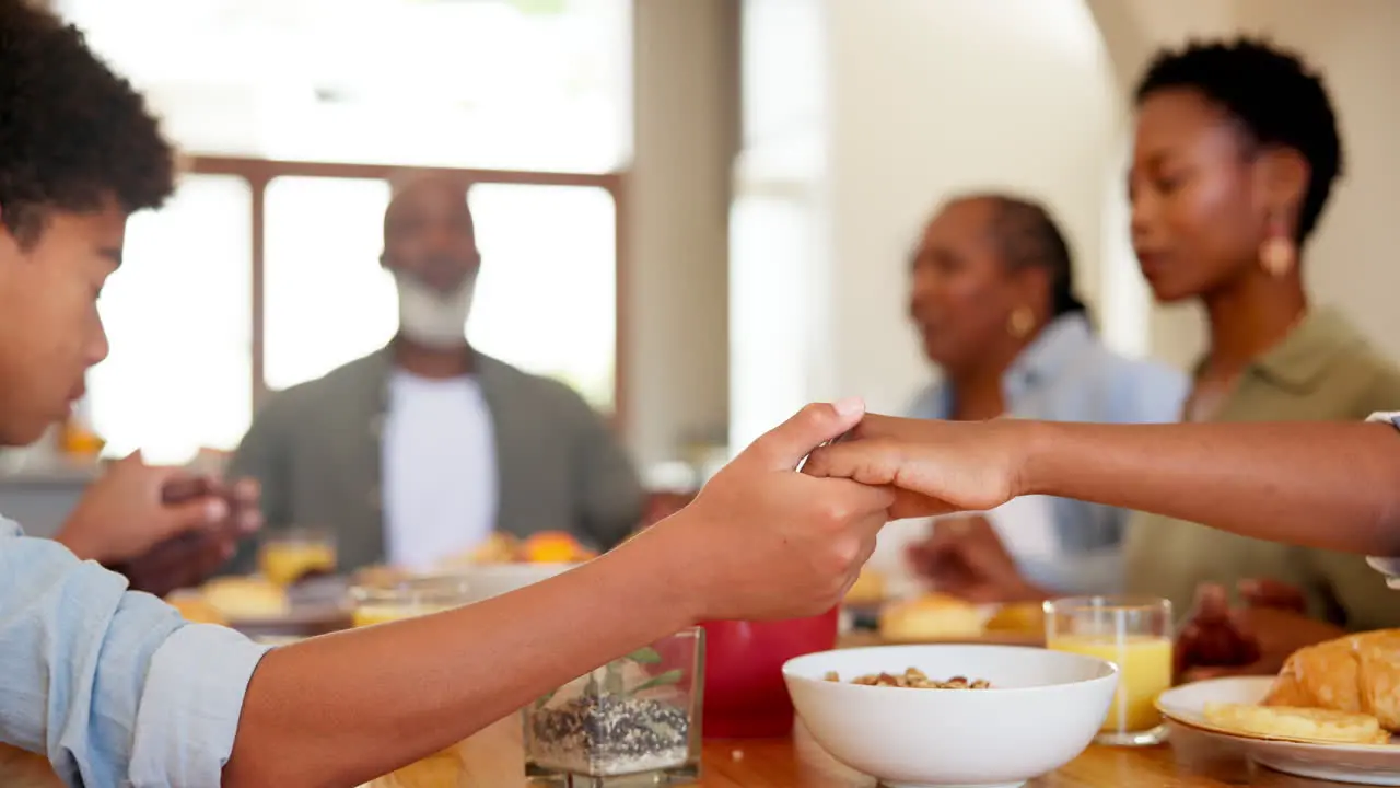 Black family praying and food in home