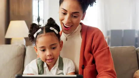 Mother girl with tablet and learning on sofa