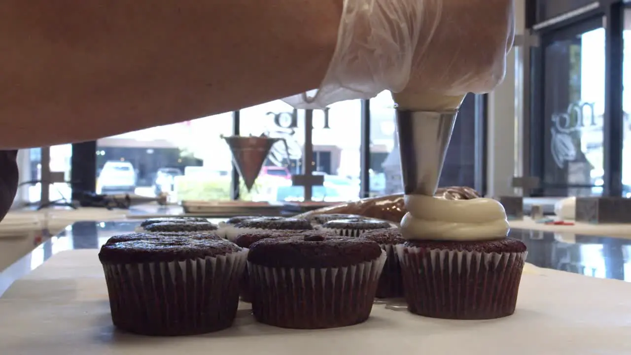 A Chef Piping Cupcakes in a Bakery During the day time