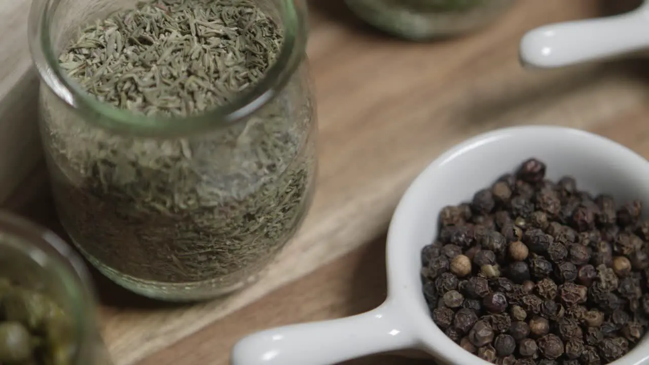 Close up panning shot of thyme and black pepper sitting in small jars