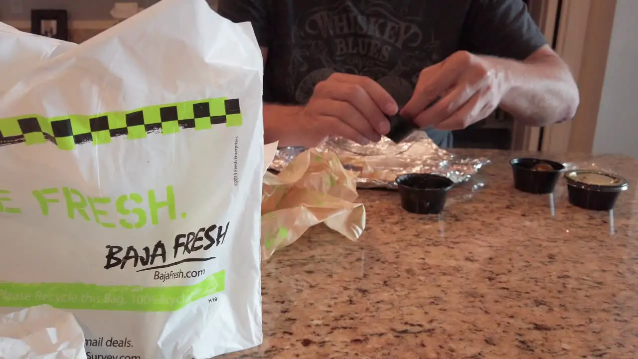 Smooth reveal shot of a man dipping chips into salsa from Baja Fresh fast food