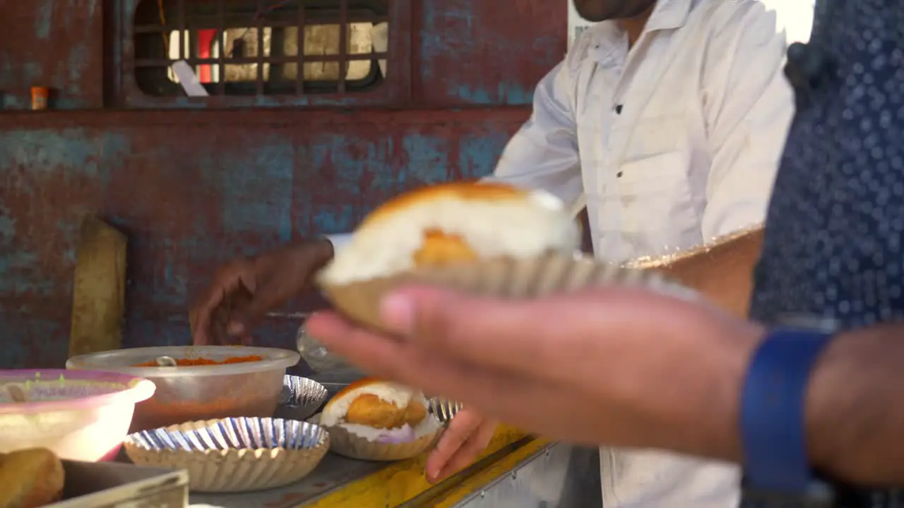 Street side small independent eatery selling tasty and spicy streetfood Vada Pav to customer