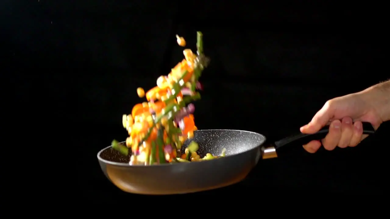 CU SLOWMOTION Chef holding Wok while tossing vegetables in a studio lighting