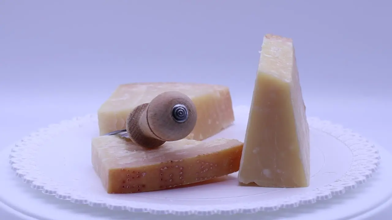 Italian Parmigiano Reggiano cheese with cheese knife rotating on a turntable