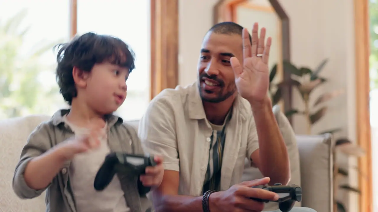 Father son and video game with high five on sofa