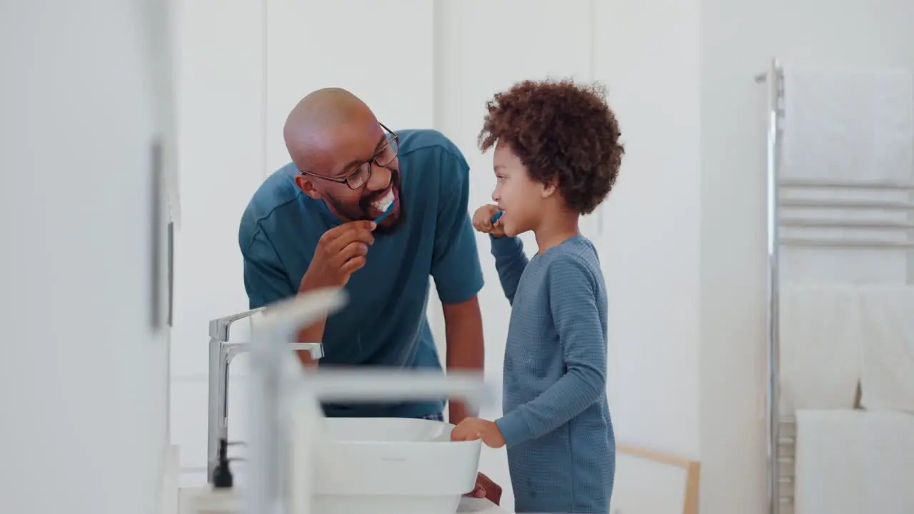 Child learning and brushing teeth with dad