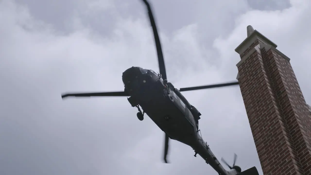 Slow motion shot of blackhawk helicopter flying over a building in the sky