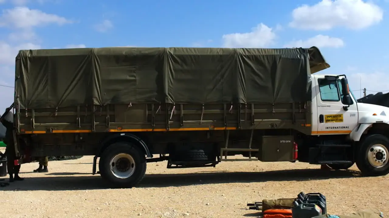 A military truck in a desert area is loaded by soldiers