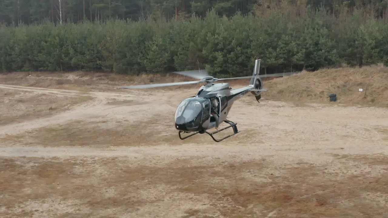 Aerial View of Military Helicopter With Soldier Holding Sniper Rifle Hovering Above Training Field Drone Shot