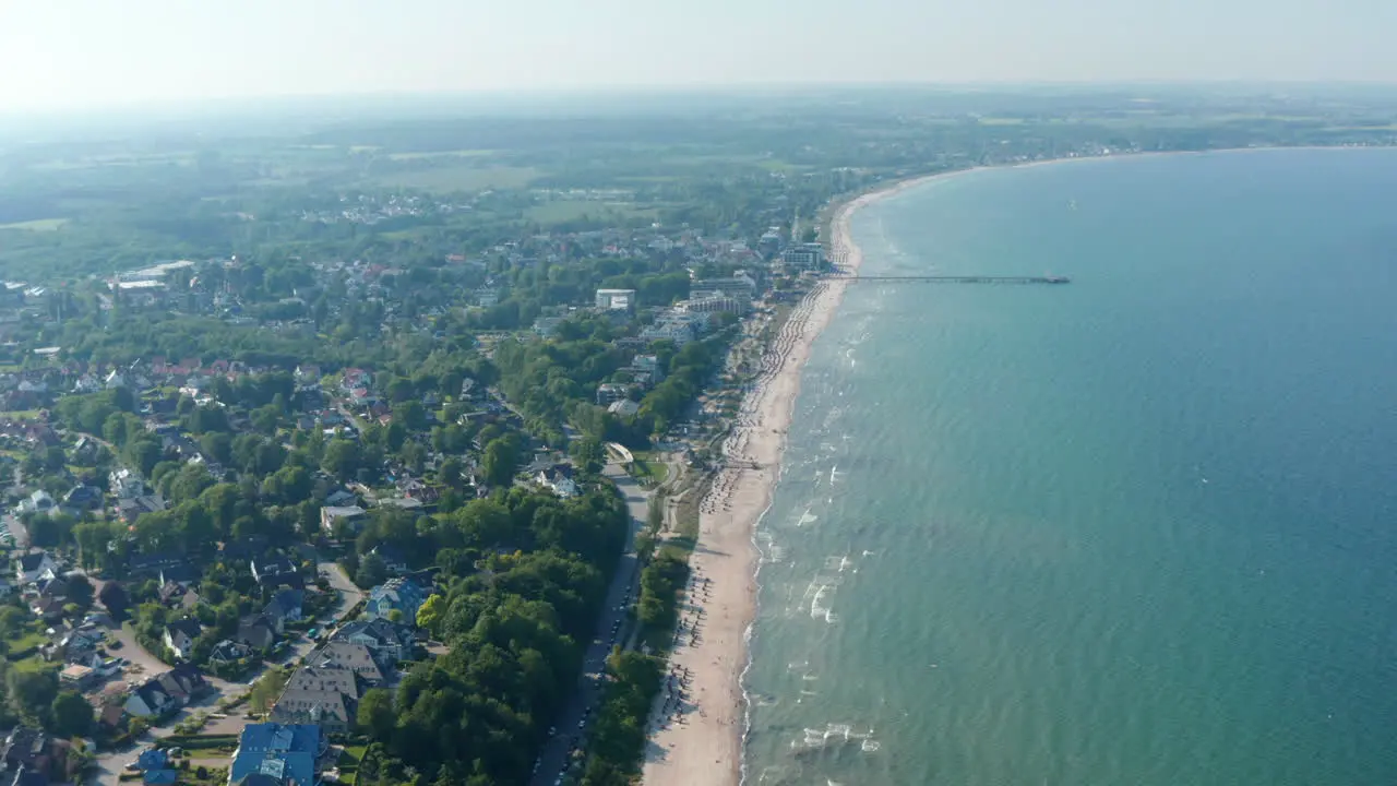 High aerial drone view of scenic summertime beach in Scharbeutz Germany dolly in sunny windy day