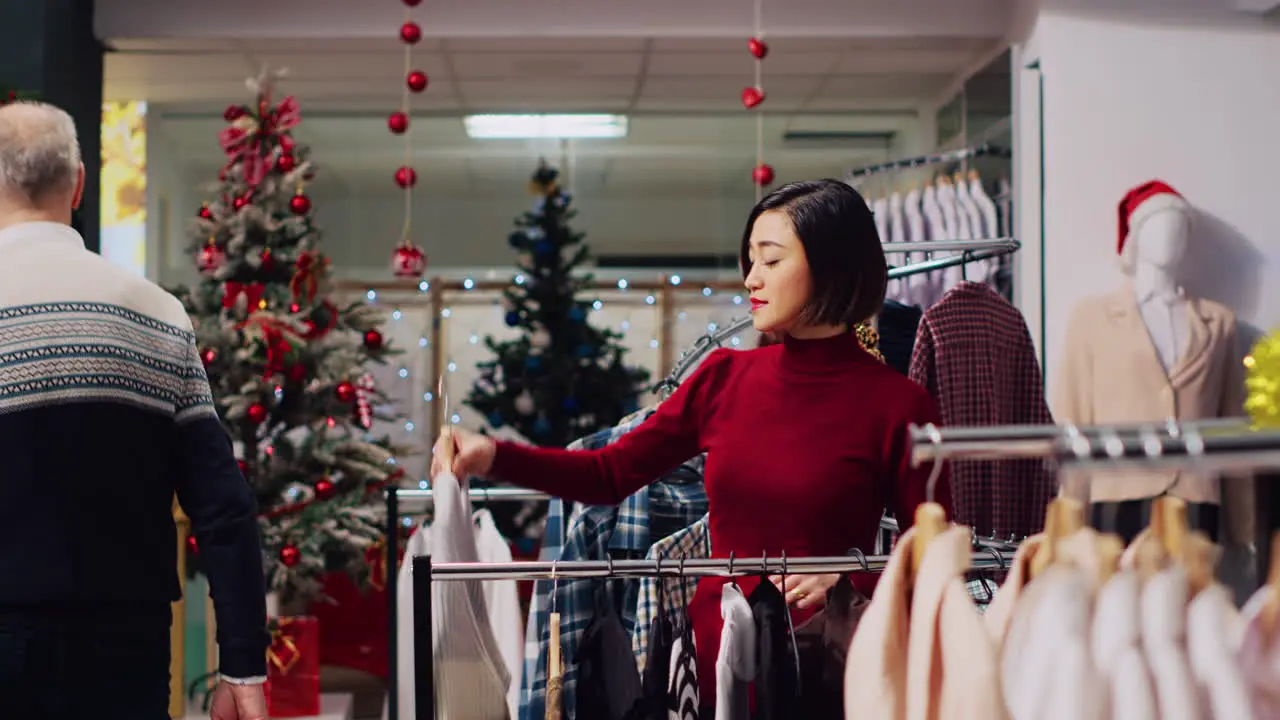 Woman browsing though clothes in festive Christmas clothing store looking to buy perfect outfit for New Years Eve party Customer in mall fashion boutique searching for ideal attire