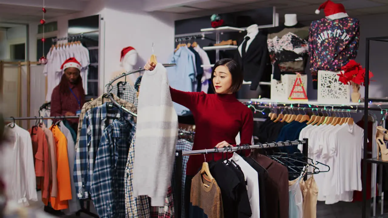 Smiling client in Christmas ornate fashion shop looking to purchase comfortable clothes on clearance taking advantage of reduced prices during holiday season promotional sales