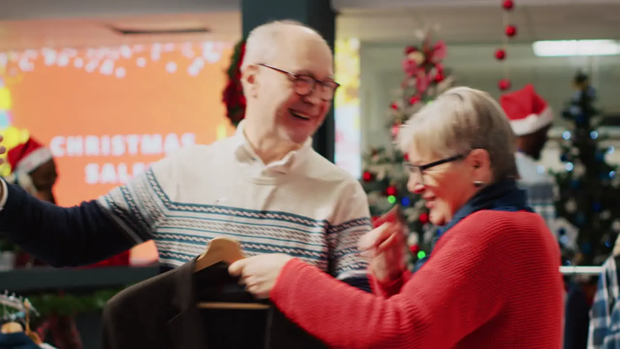 Joyful older couple using smartphone to chat with nephew in online videocall while shopping for clothes asking for advice on picking perfect xmas gift during Christmas holiday season