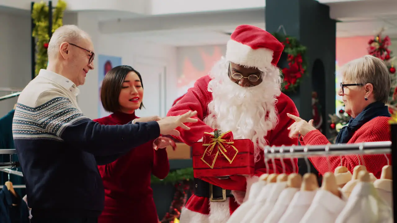 Customers participating in Christmas raffle hold by employee dressed as Santa Claus in clothing store Asian woman excited after winning winter holiday season promotional fashion shop contest