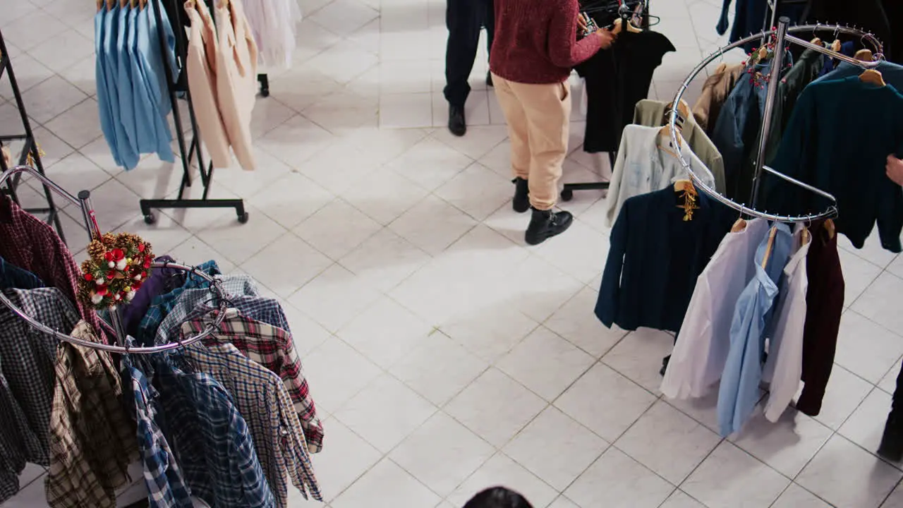 Top down view of customers roaming around busy shopping mall clothing store aisles looking to buy clothes as gifts for family and friends during Christmas promotional sales event