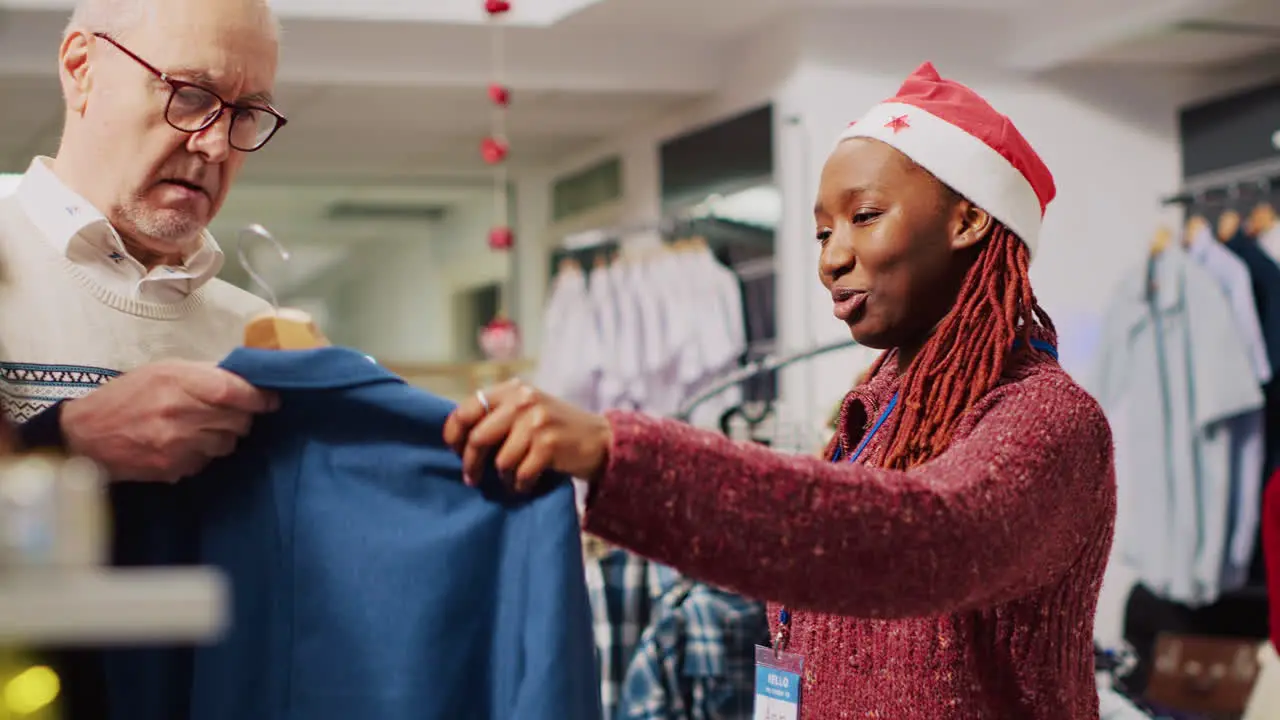 Helpful retail assistant helping senior man blazer size measurements picking best fitting garment in festive decorated clothing store during winter Christmas holiday season