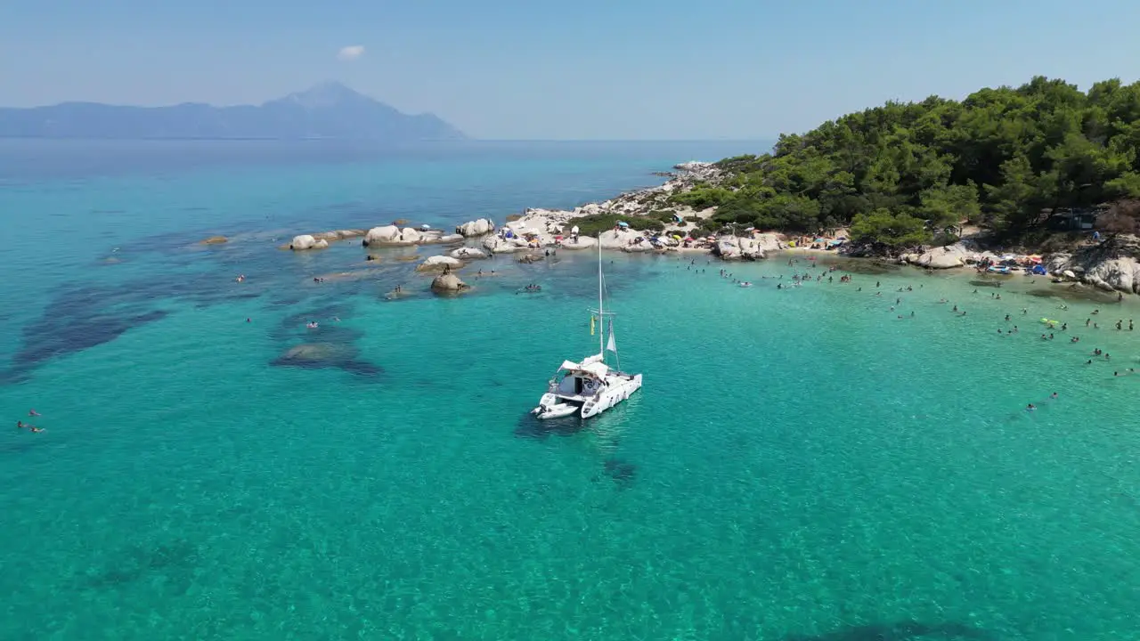 Catamaran Boat and People Swim in Turquoise Blue Bay in Halkidiki Greece Aerial 4k Circling