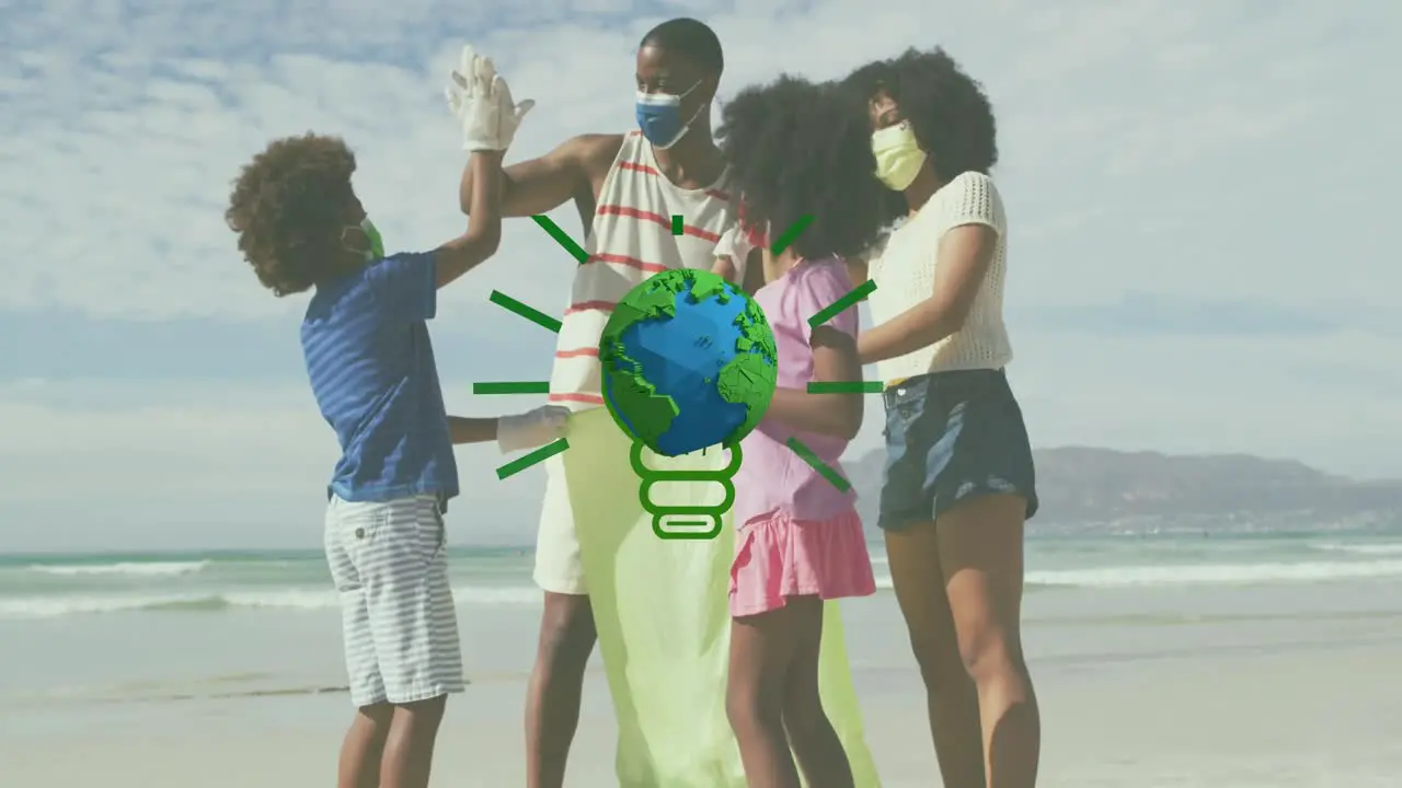 Animation of globe over african american family with face masks picking waste on sunny beach