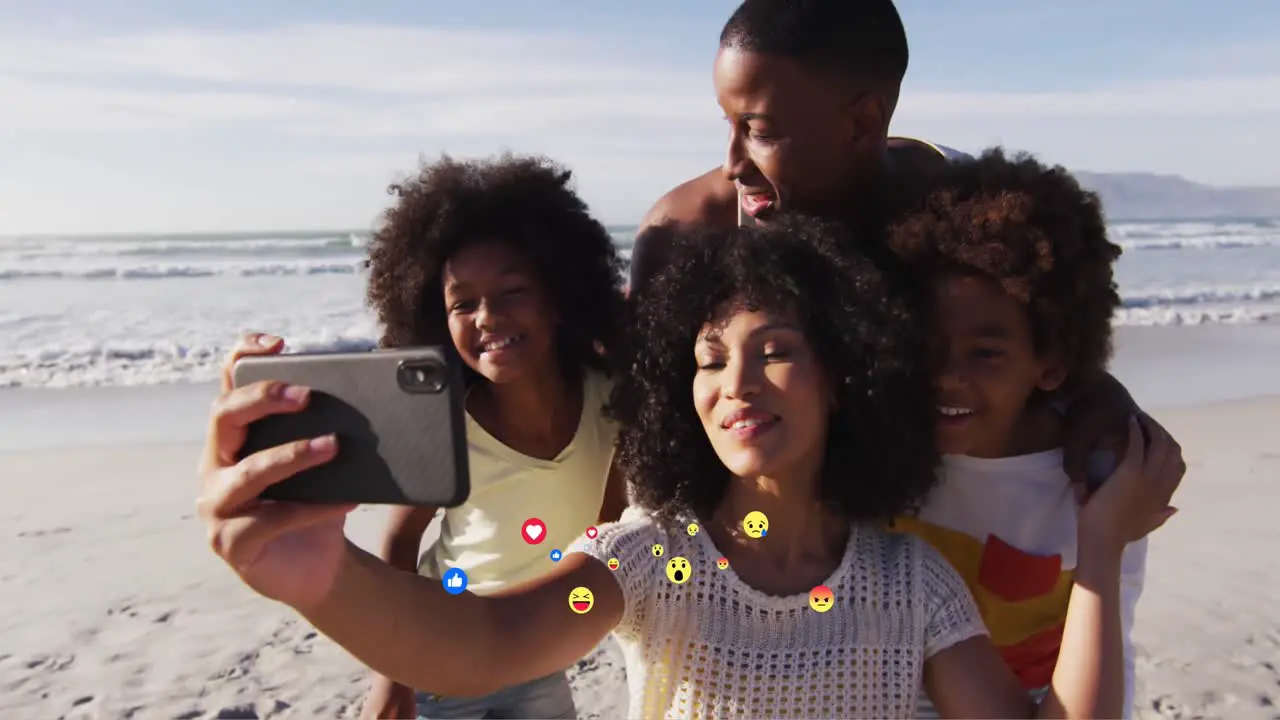 Animation of media icons over happy african american family taking selfie on sunny beach