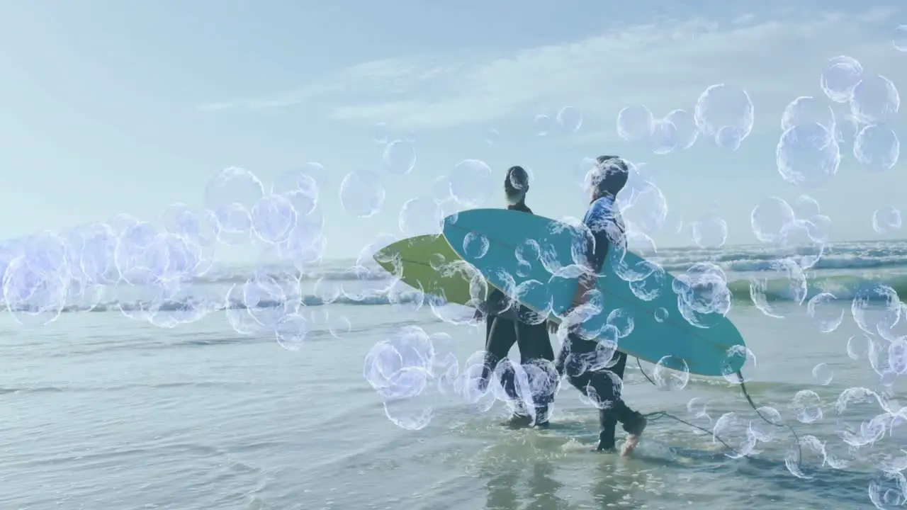 Animation of bubbles over senior african american couple with surfboards on sunny beach