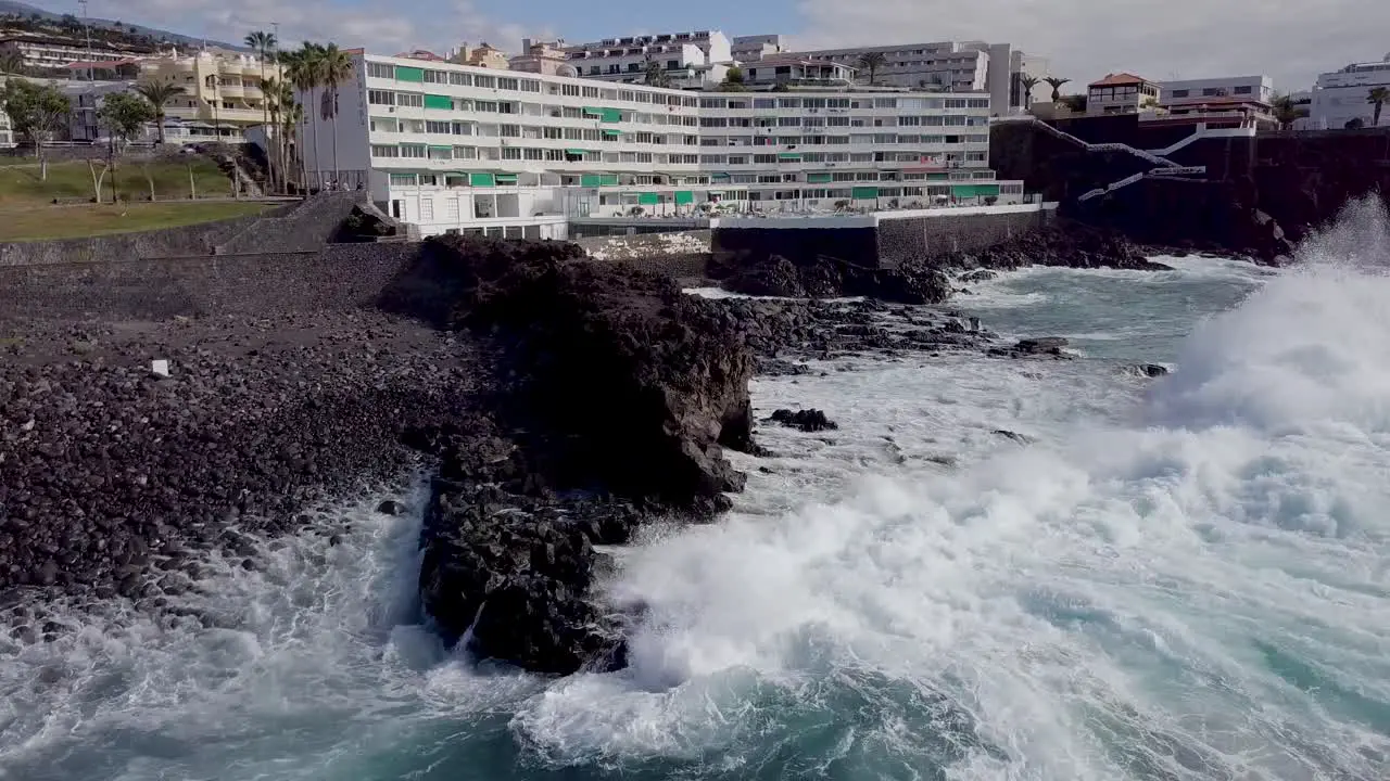 aerial view of hotel tourist resort in playa de piedra Tenerife island Santa Cruz drone fly above ocean waves crashing in rock beach tropical paradise