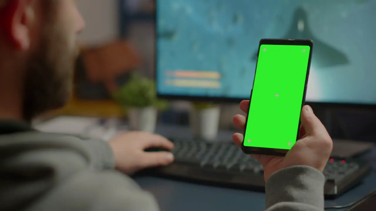 Competitive gamer looking at smartphone with green screen display