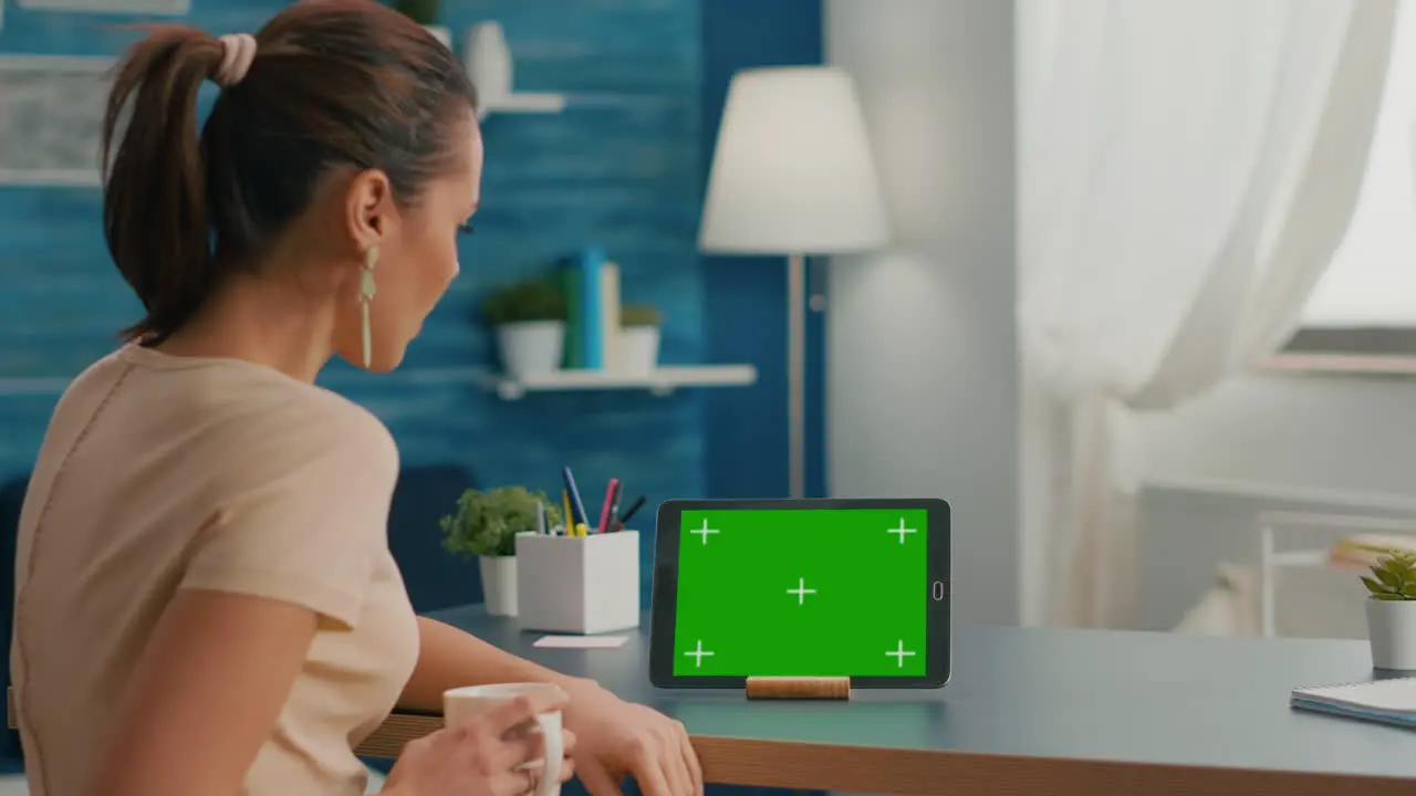 Caucasian female looking at tablet computer with mock up green screen