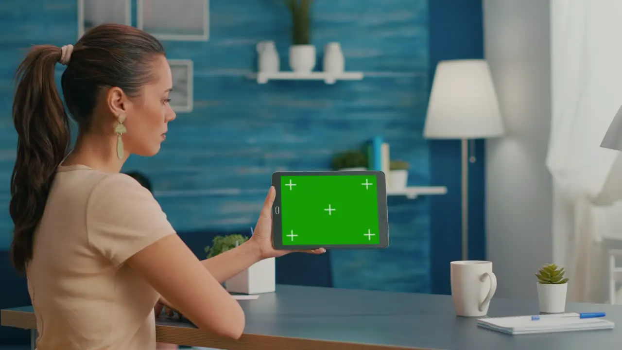 Woman looking at tablet computer with mock up green screen