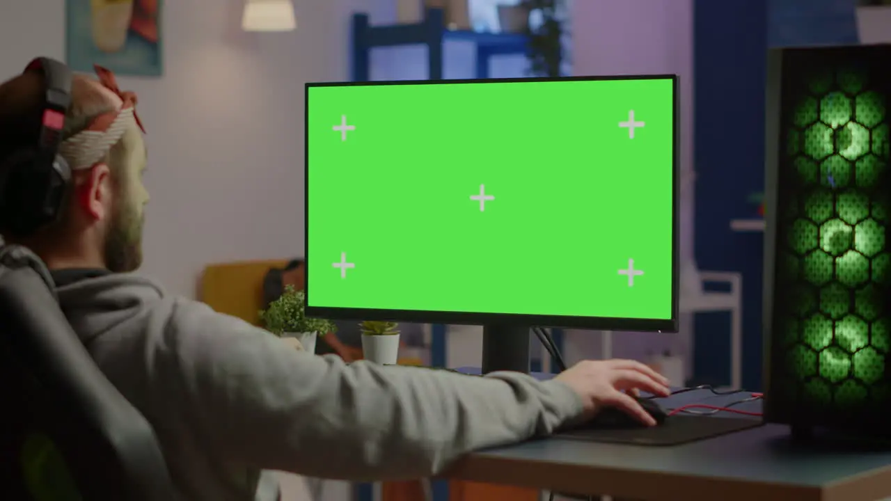 Gamer playing video games on powerful computer with green screen desktop