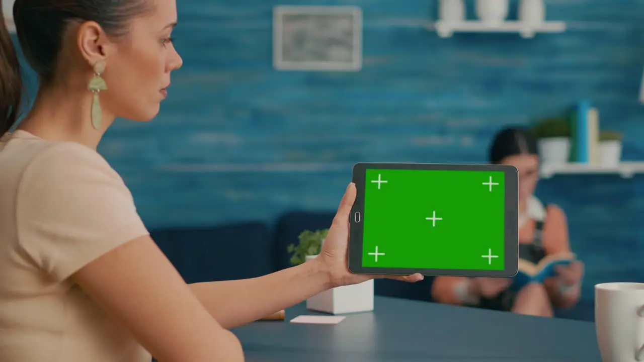 Back view of woman holding tablet computer with mock up green screen