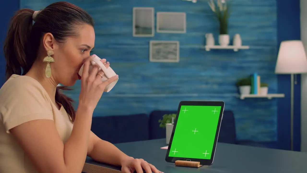 Business woman reading emails while drinking coffee sitting at office desk table