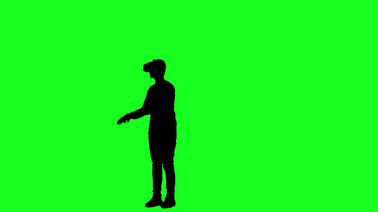 Silhouette of a man wearing VR glasses playing a game on green screen