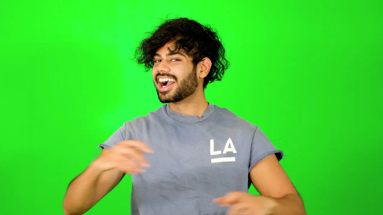 Indian guy showing up and saying hello to the camera with waving hand with green background green screen