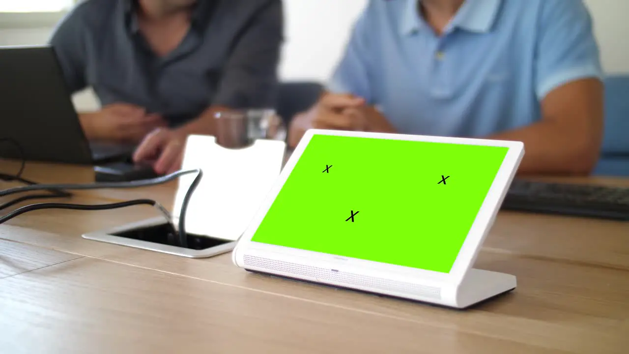 An iPad displaying a green page during a corporate meeting in a boardroom