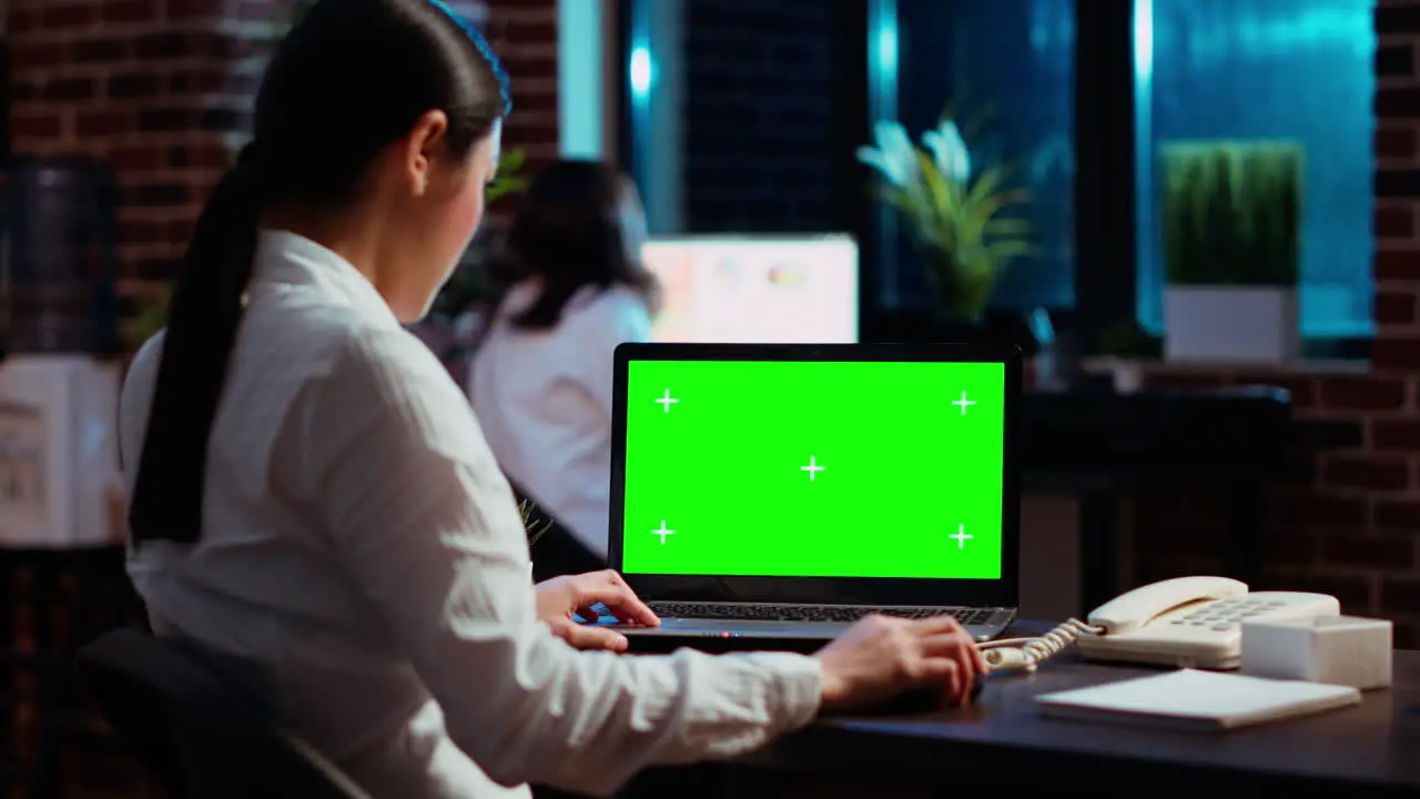 Worker looking over green screen laptop display researching data