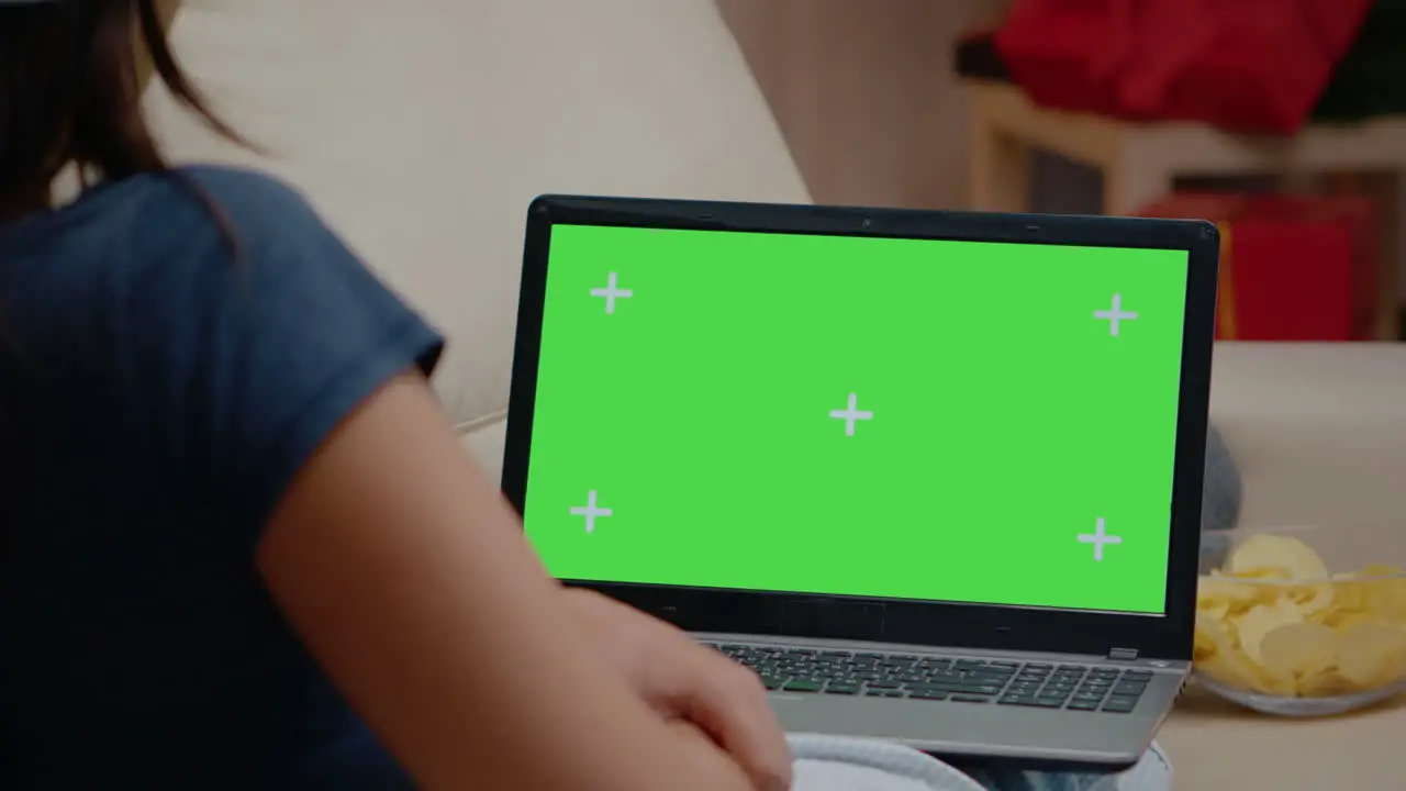 Close up of person watching horizontal green screen on laptop