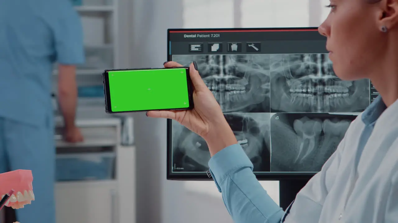 Close up of dentist analyzing smartphone with green screen