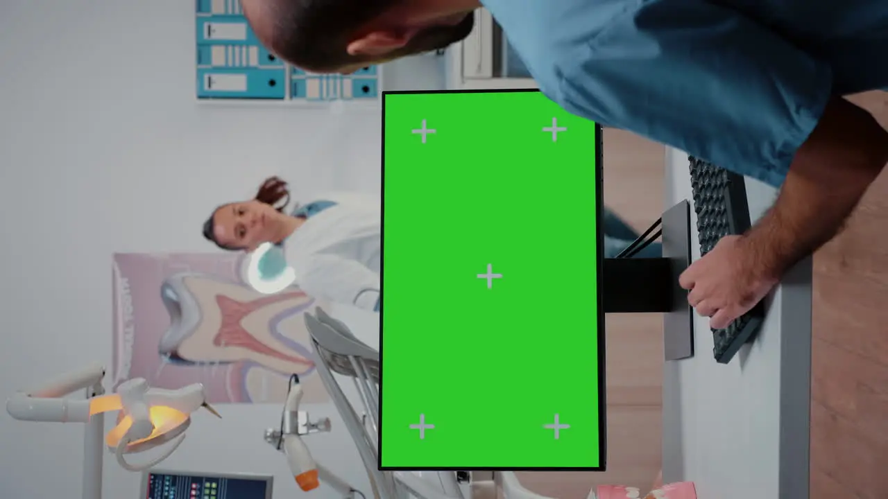 Vertical video Assistant looking at horizontal green screen on computer