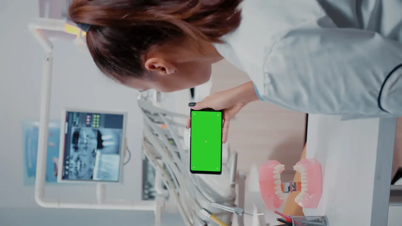 Vertical video Specialist analyzing mobile phone with green screen