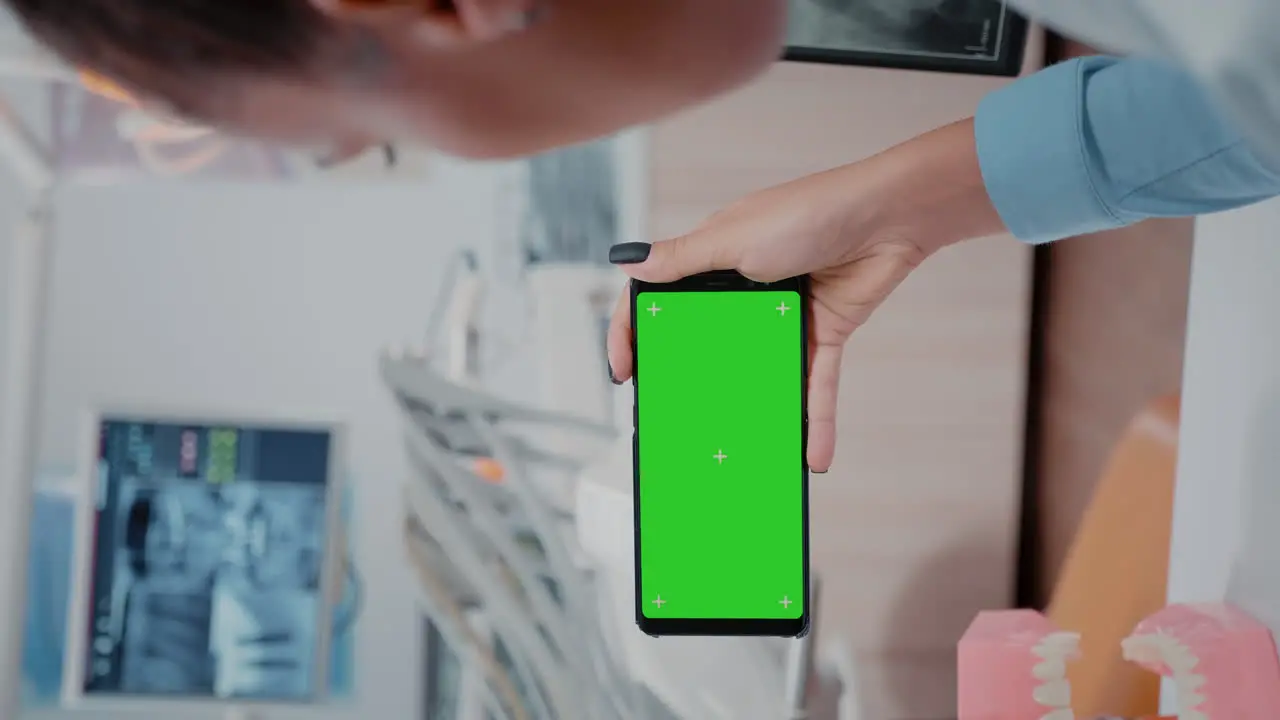 Vertical video Woman holding smartphone with horizontal green screen