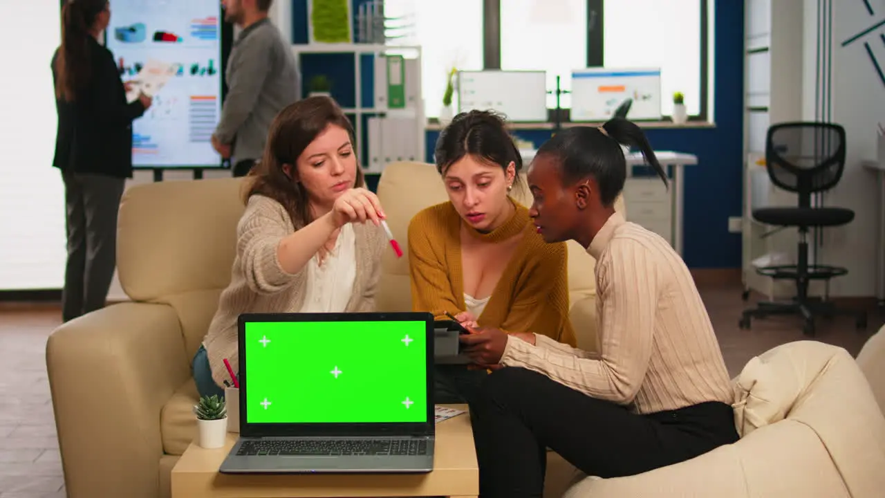 Businesswomen discussing in back of laptop with greenscreen