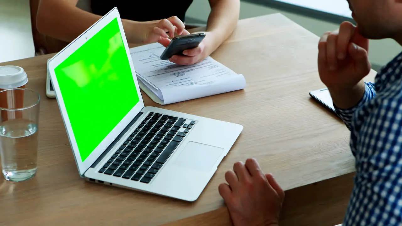 Executives using mobile phone and laptop at desk