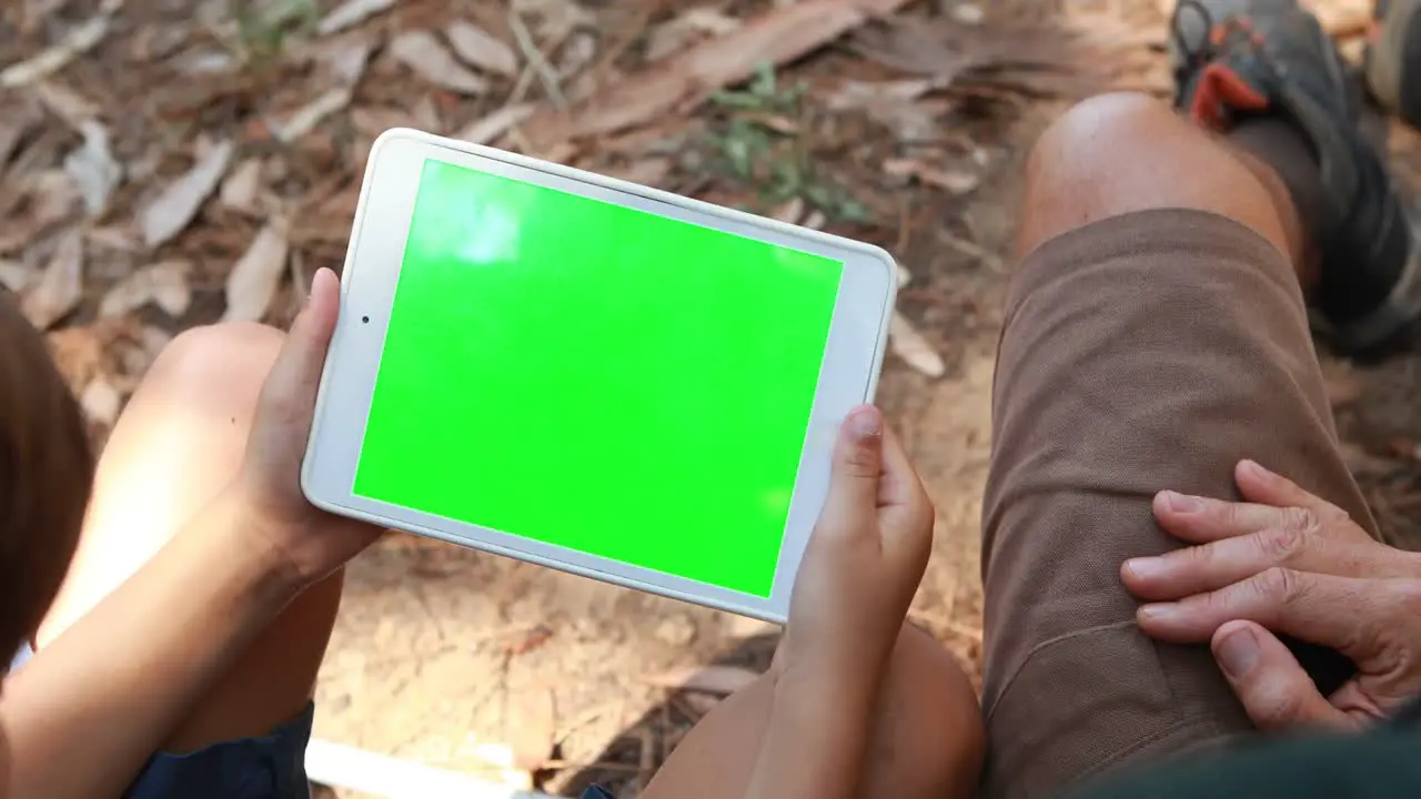 Father and son using digital tablet outside tent