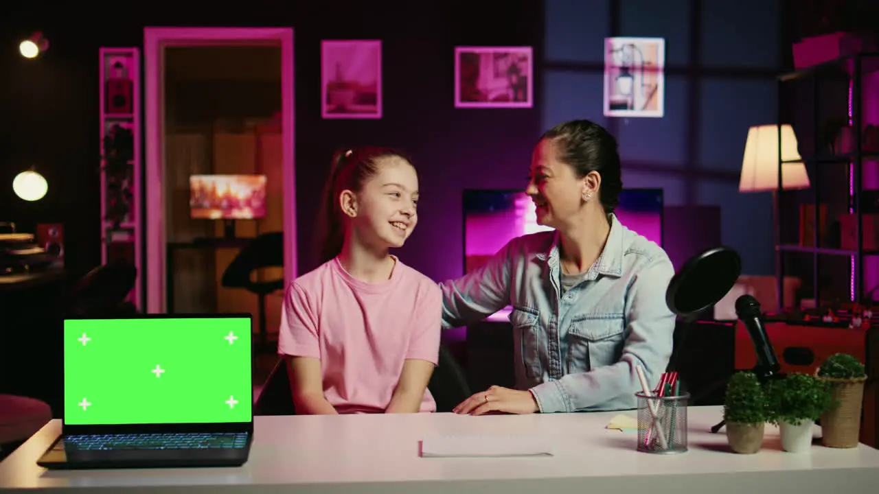 Mom and her young kid recording content next to chroma key notebook