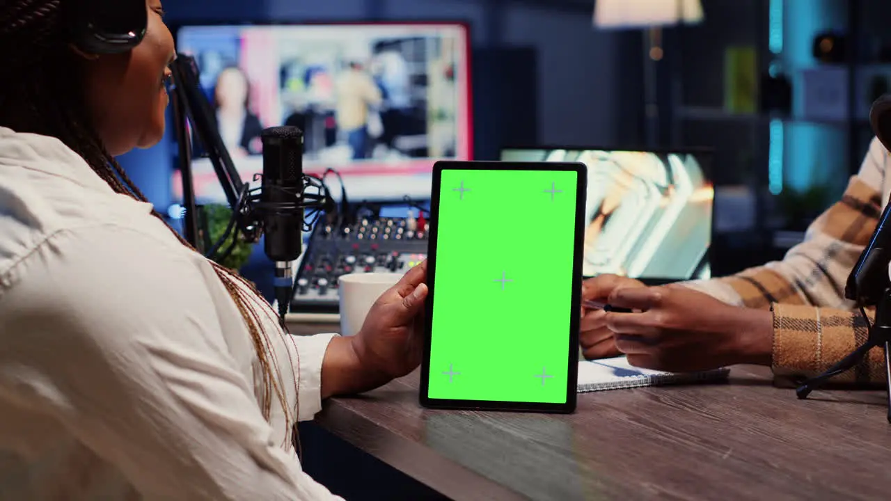 Green screen tablet hold by woman on podcast discussing with guest during marathon stream