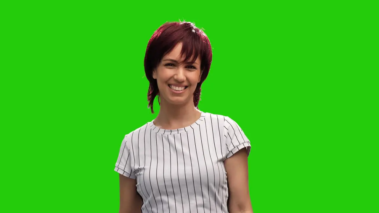 Beautiful female model posing on green screen blows kiss and shows thumb up gesture