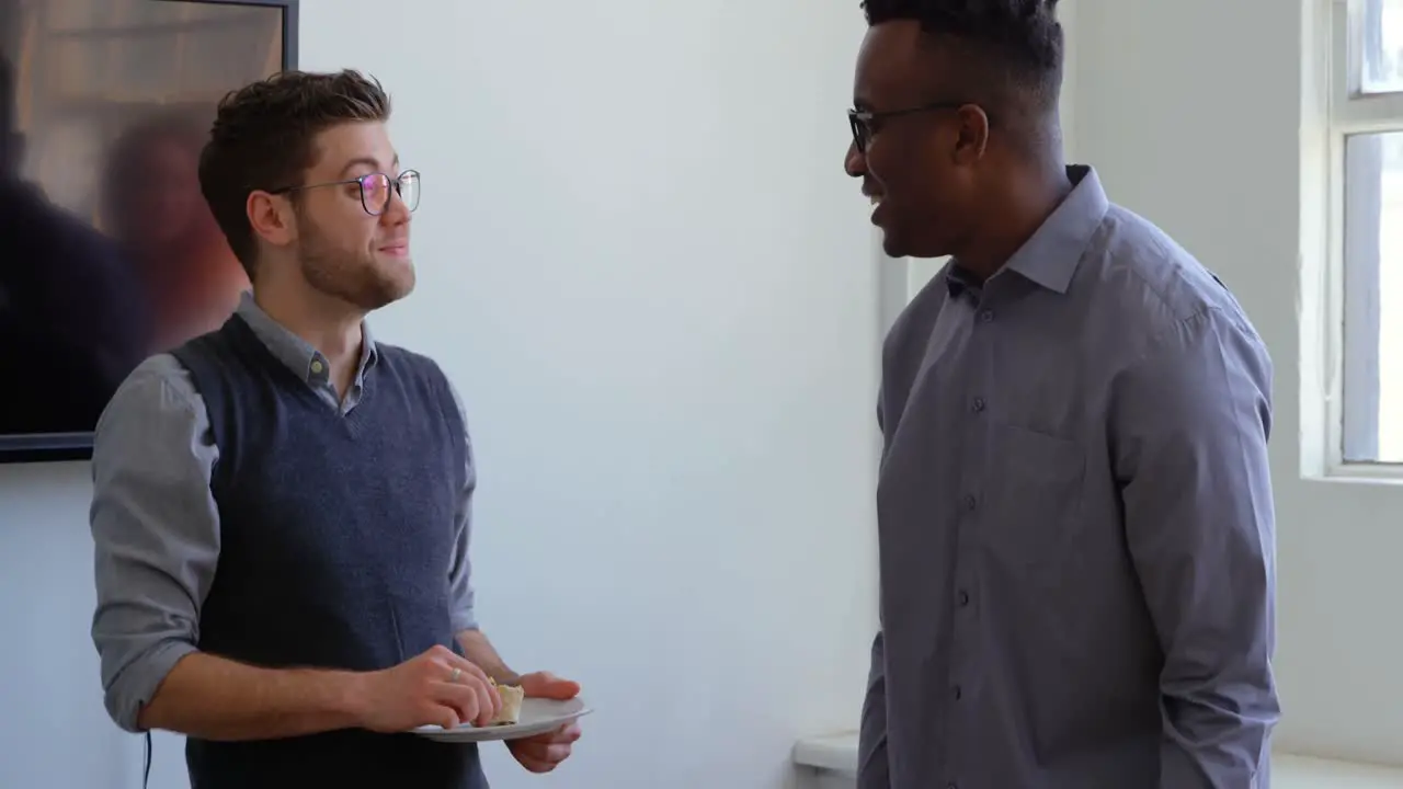 Side view of happy young mixed-race business team eating food in a modern office 4k