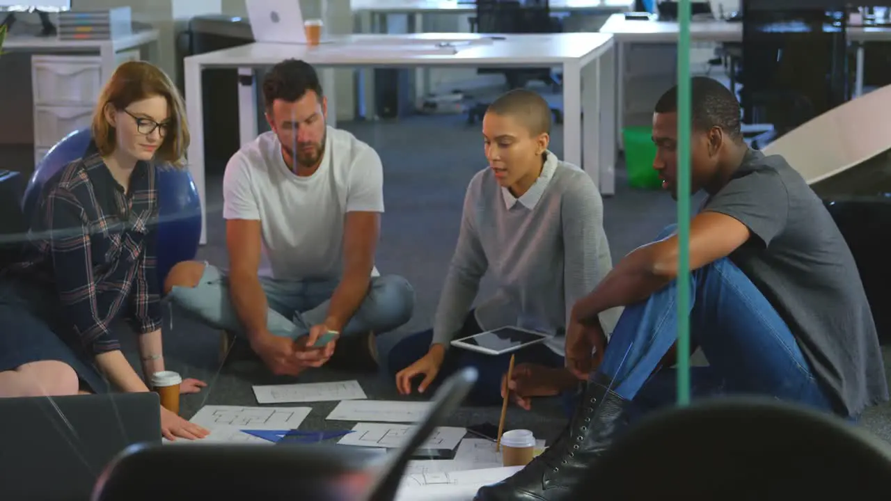 Young mixed race business team discussing over documents in office 4k