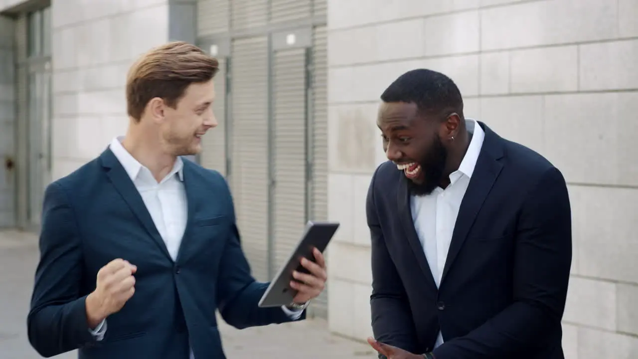 Businessmen reading good news on tablet Professionals celebrating victory